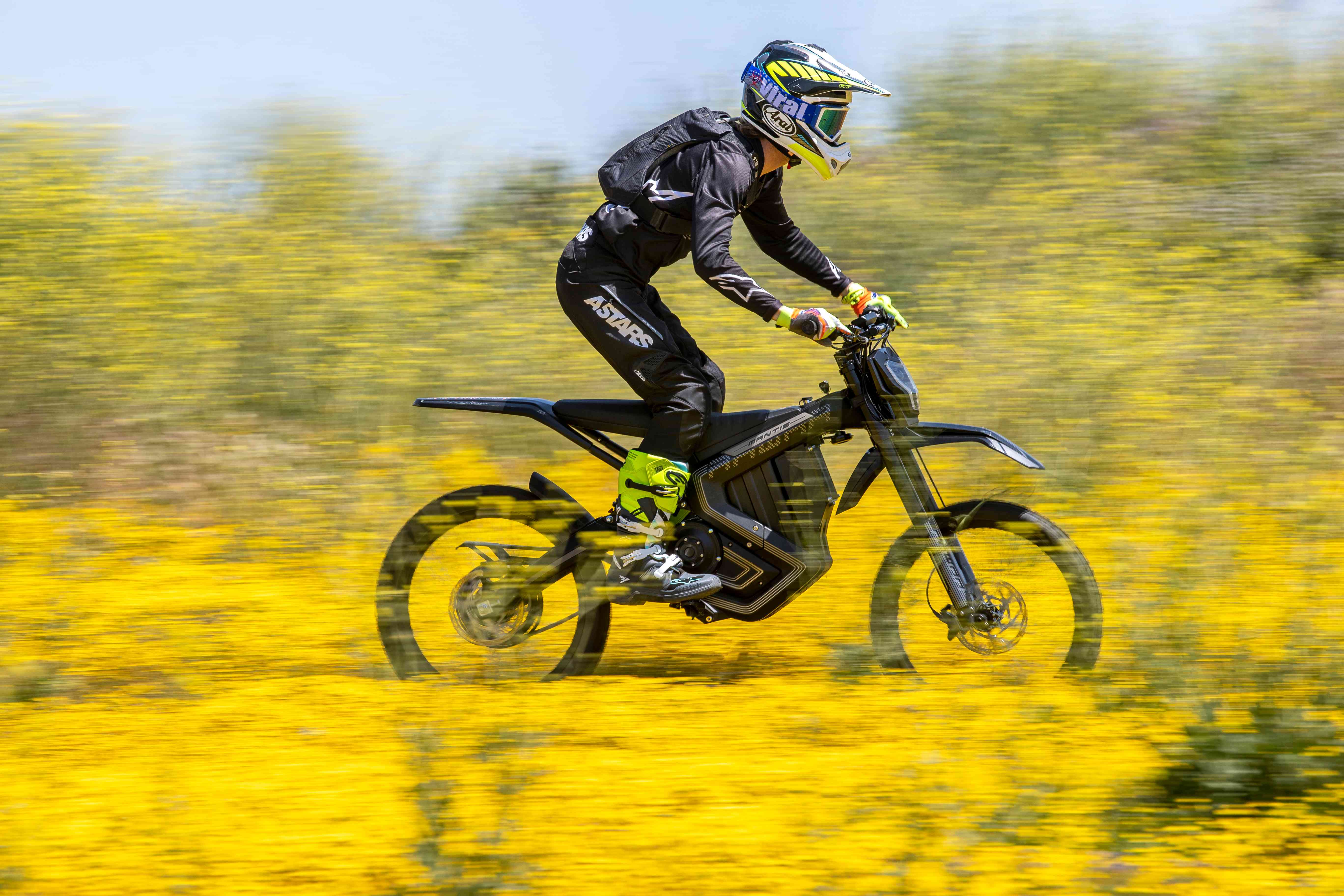 A man riding Mantis dirtbike with flower background